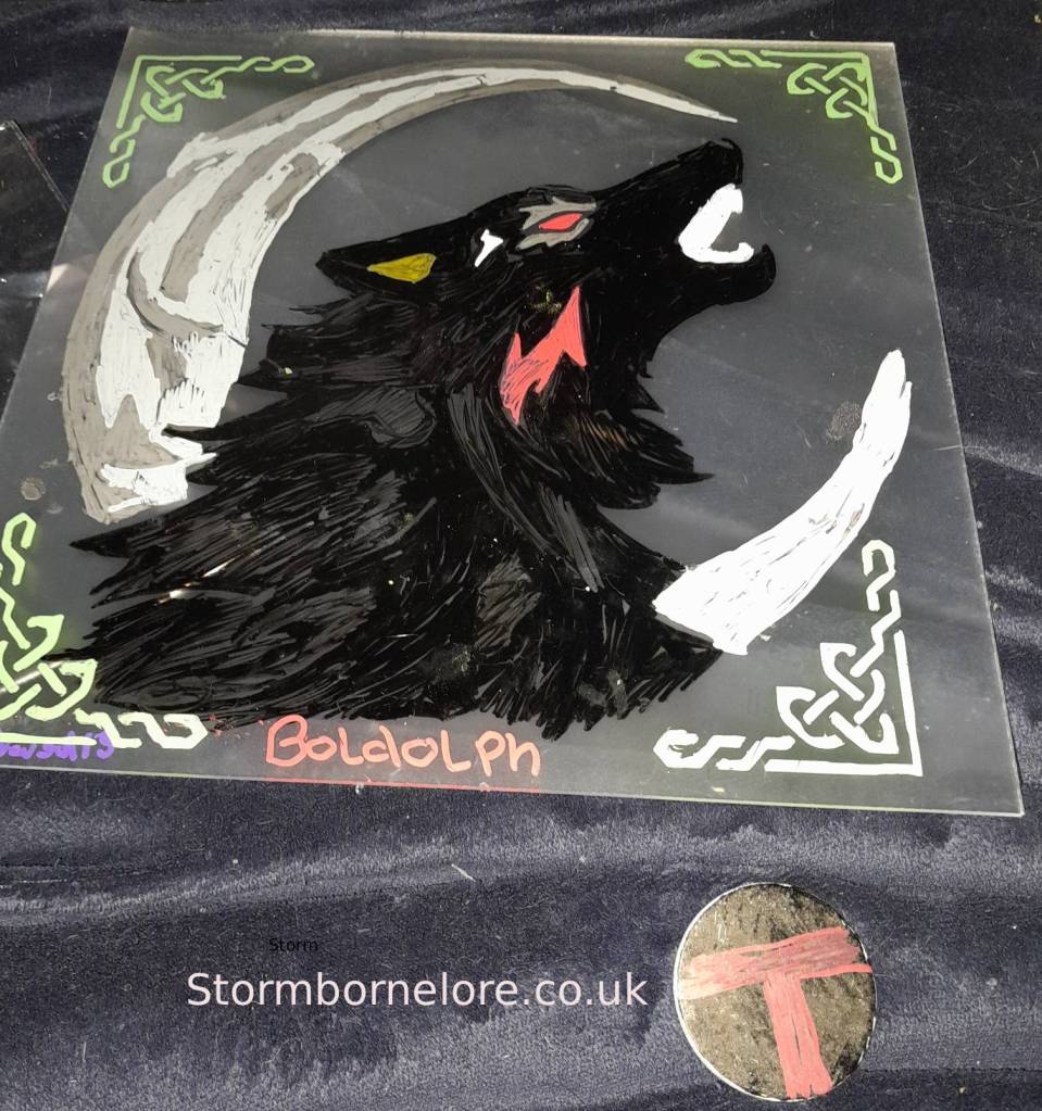 A painted representation of a black wolf howling with glowing red eyes, set against a crescent moon, decorated with Celtic patterns. The name 'Boldolph' is written in vibrant colors at the bottom.