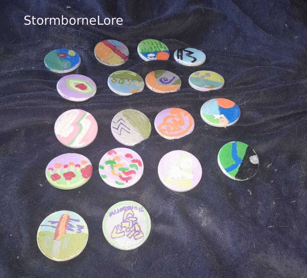 A collection of hand-painted rune stones featuring various colorful designs, displayed on a dark fabric surface.