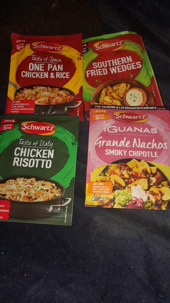 Four packaged meal kits from Schwartz featuring 'One Pan Chicken & Rice', 'Southern Fried Wedges', 'Chicken Risotto', and 'Grande Nachos Smoky Chipotle'.